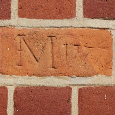brick with initials and date carved in